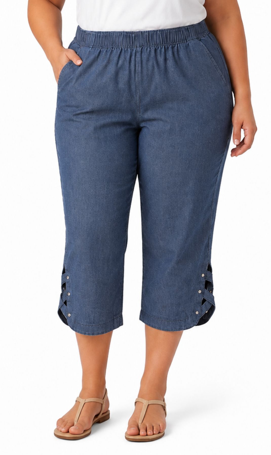 A women shown from wearing blue cropped pants with lace-up detailing at the lower hems, paired with a white top and tan sandals, against a plain white background.