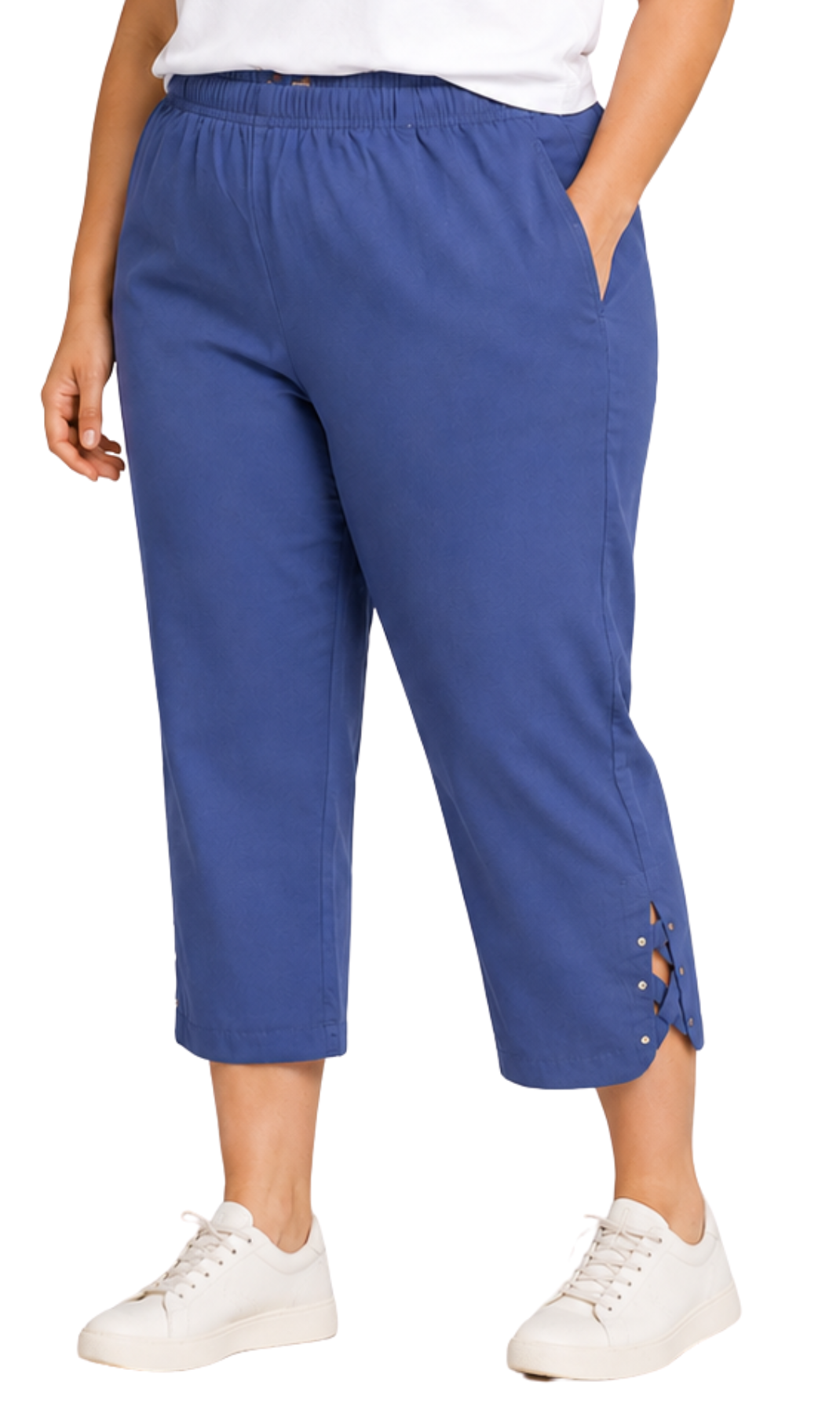 A person wearing blue cropped pants with side cutout details and white sneakers, shown from the waist down against a plain white background.