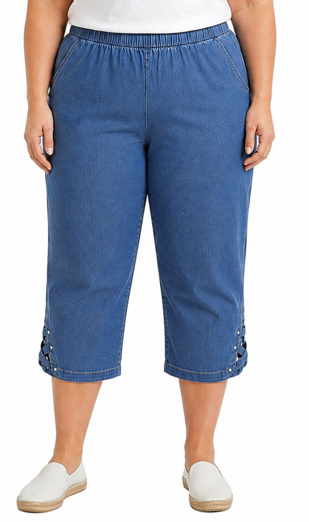 A person wearing blue cropped denim pants with an elastic waistband and lace-up side details, paired with a white top and white slip-on shoes, against a plain white background.
